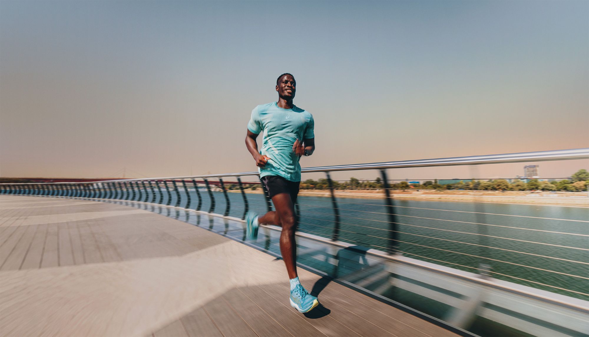 Biegacz w turkusowych butach ASICS GEL-NIMBUS 29 na promenadzie nad rzeką