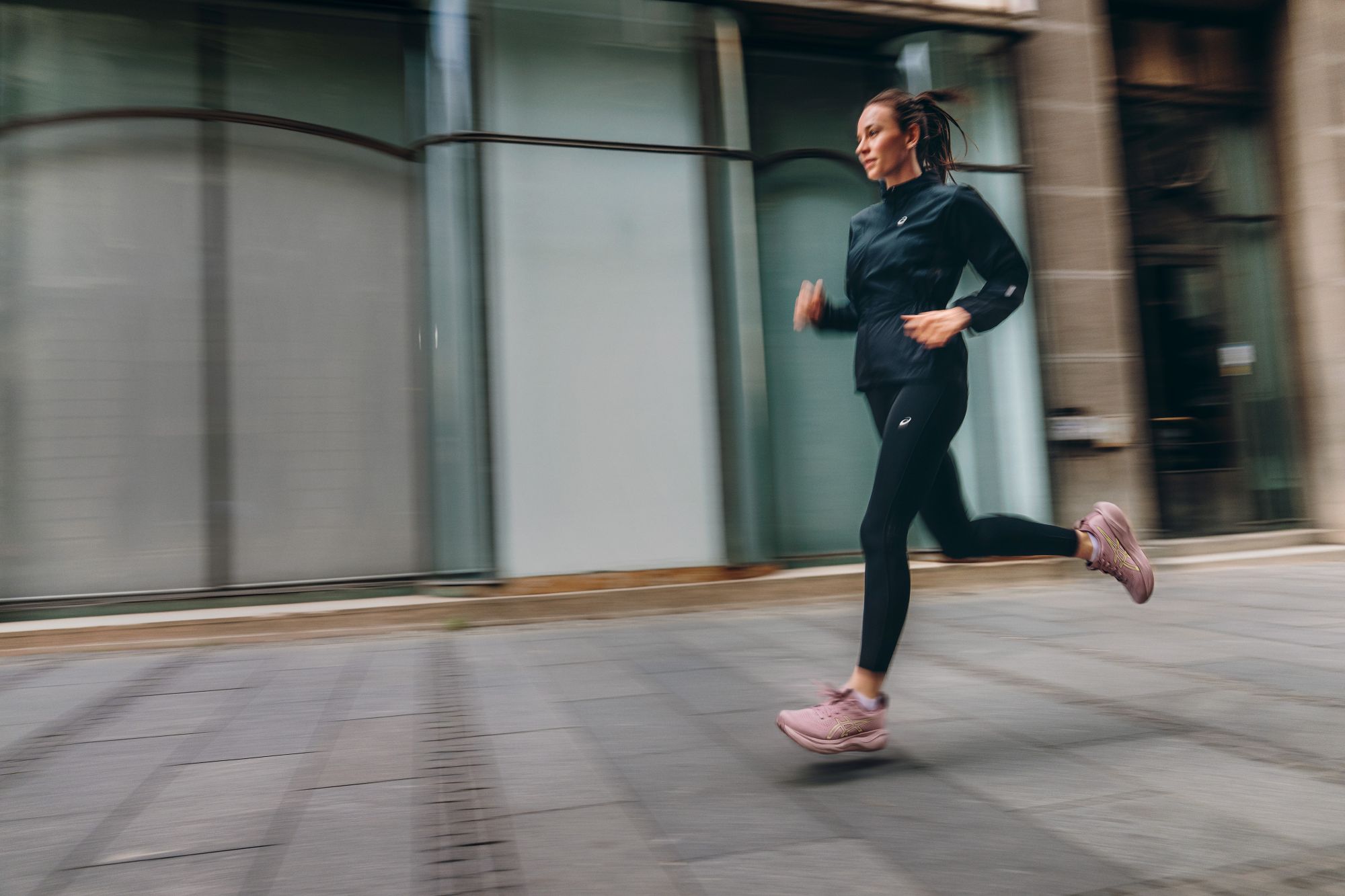 Biegaczka w różowych butach ASICS GEL-NIMBUS 29 na miejskim chodniku