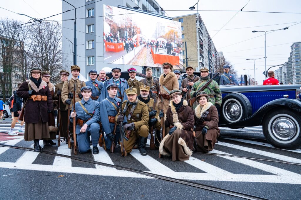 Rekonstruktorzy w historycznych mundurach przy zabytkowym samochodzie podczas Biegu Niepodległości